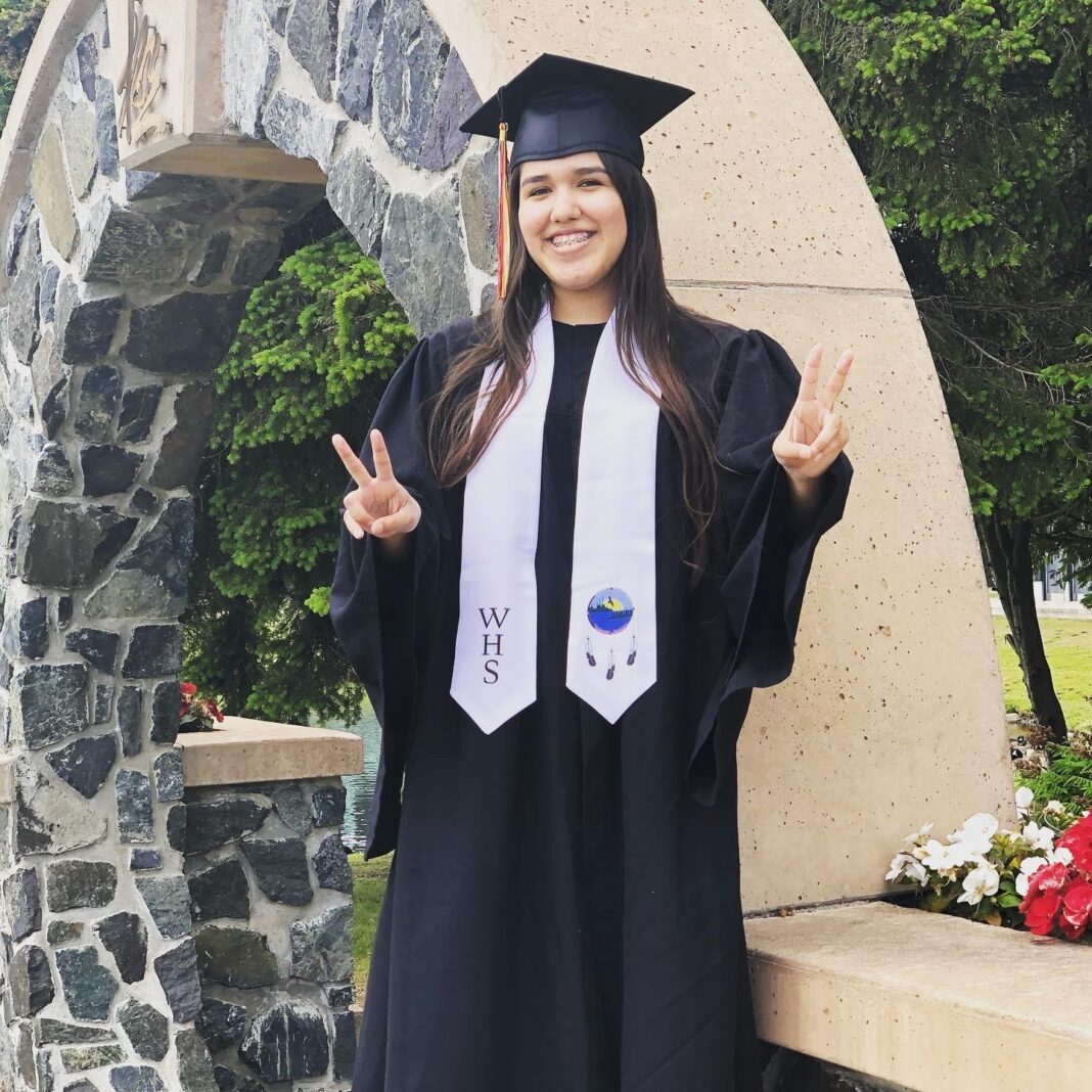 Girl in graduation clothing doing a piece sign