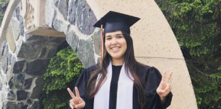 Girl in graduation clothing doing a piece sign