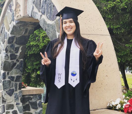 Girl in graduation clothing doing a piece sign